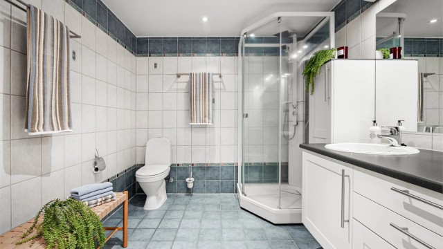 Badet er fra byggeåret og har flislagt gulv med varmekabler, dusjkabinett og downlights i himlingen.