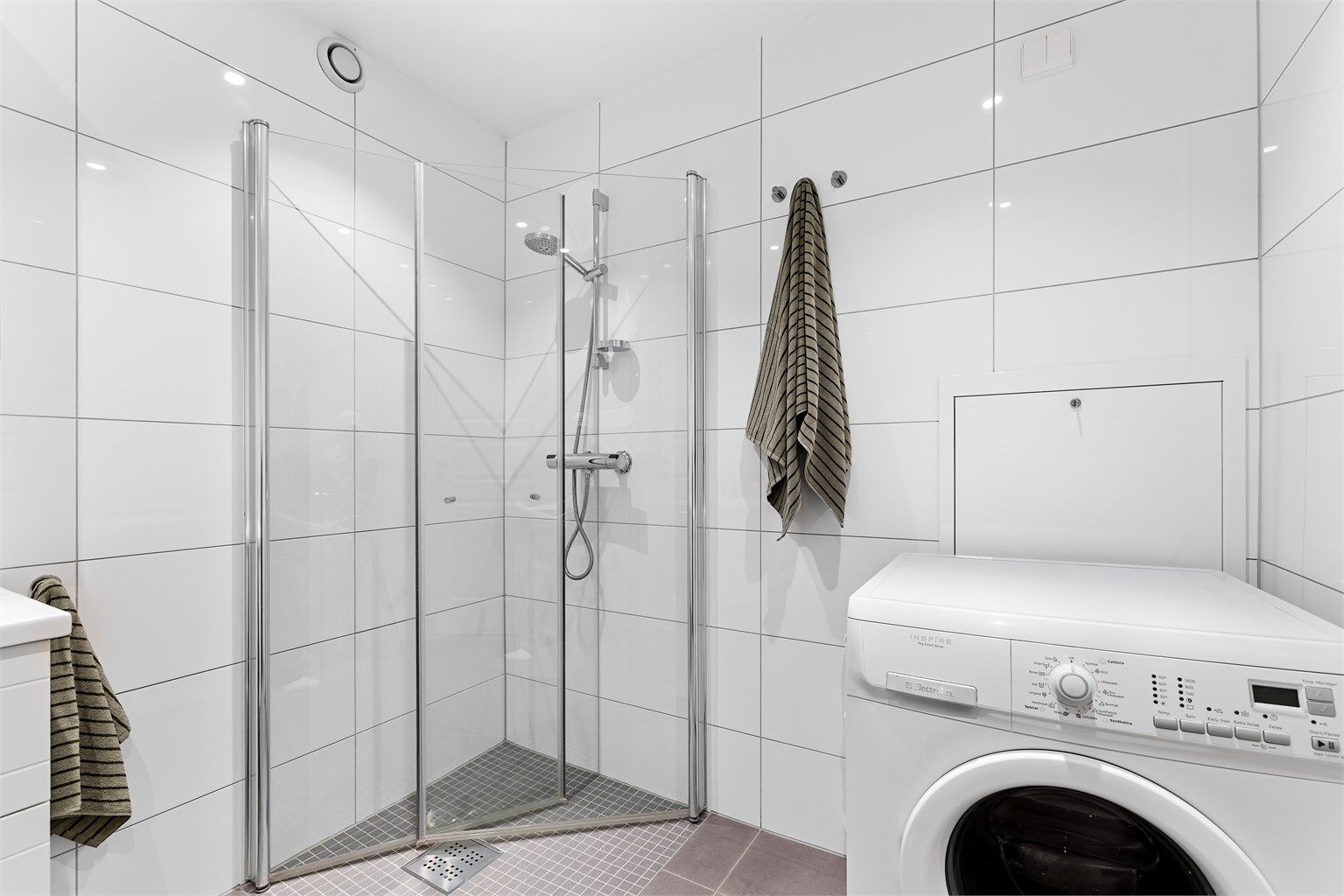 BDusjhjørne med innfellbare glassdører og opplegg for vaskemaskin.