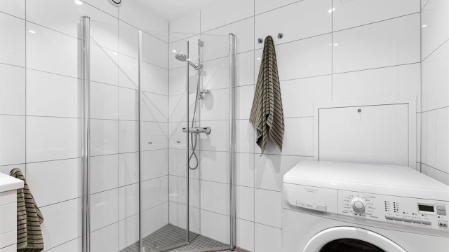 BDusjhjørne med innfellbare glassdører og opplegg for vaskemaskin.