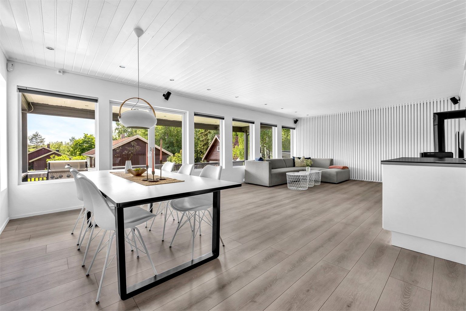 Stuen føles luftig og innbydende med store vindusflater langs hele veggen, som slipper inn rikelig med sollys, samt god takhøyde.