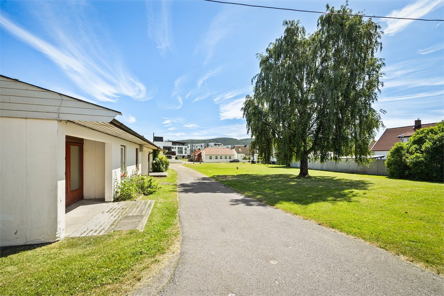 Tomten er tilnærmet flat og opparbeidet med asfalterte veier, plenarealer og diverse beplantninger.