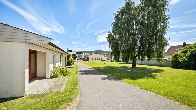 Tomten er tilnærmet flat og opparbeidet med asfalterte veier, plenarealer og diverse beplantninger.