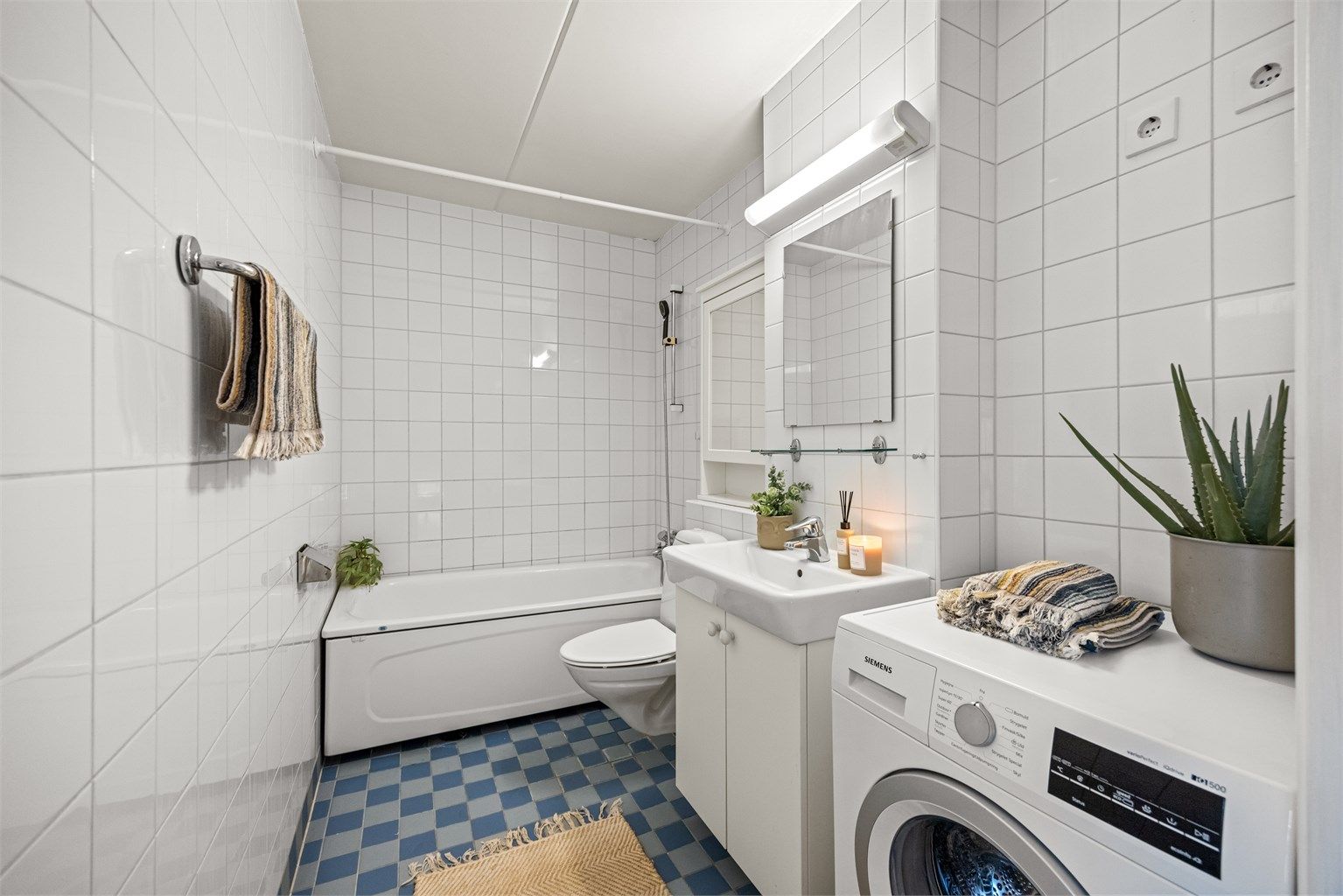 Badet er flislagt med gulvvarme, badekar og vegghengt toalett.