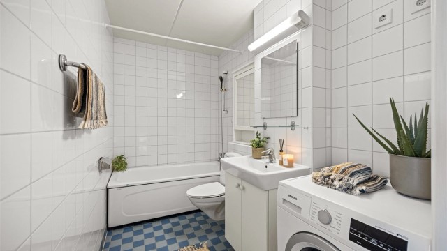 Badet er flislagt med gulvvarme, badekar og vegghengt toalett.