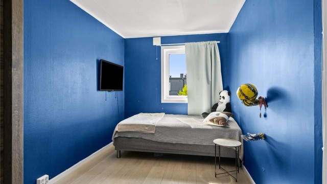 Soverom med plass til seng og oppbevaringsmøbler.