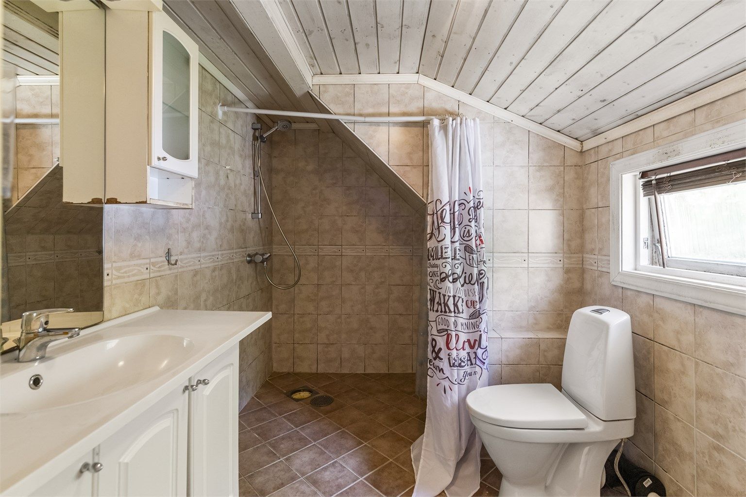 Badet er innredet med det du trenger - toalett, servant i innredning og dusj, samt opplegg for vaskemaskin. Rommet har behov for renovering.