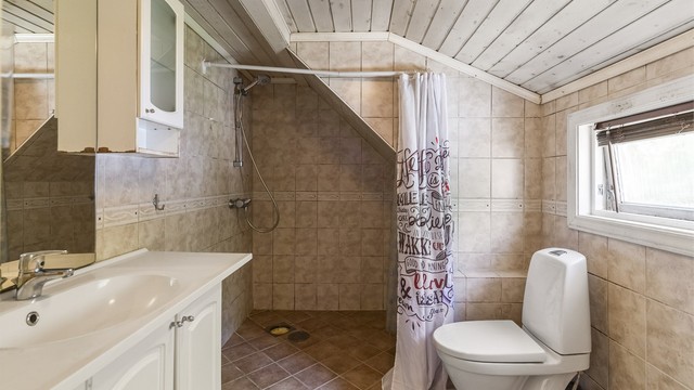 Badet er innredet med det du trenger - toalett, servant i innredning og dusj, samt opplegg for vaskemaskin. Rommet har behov for renovering.