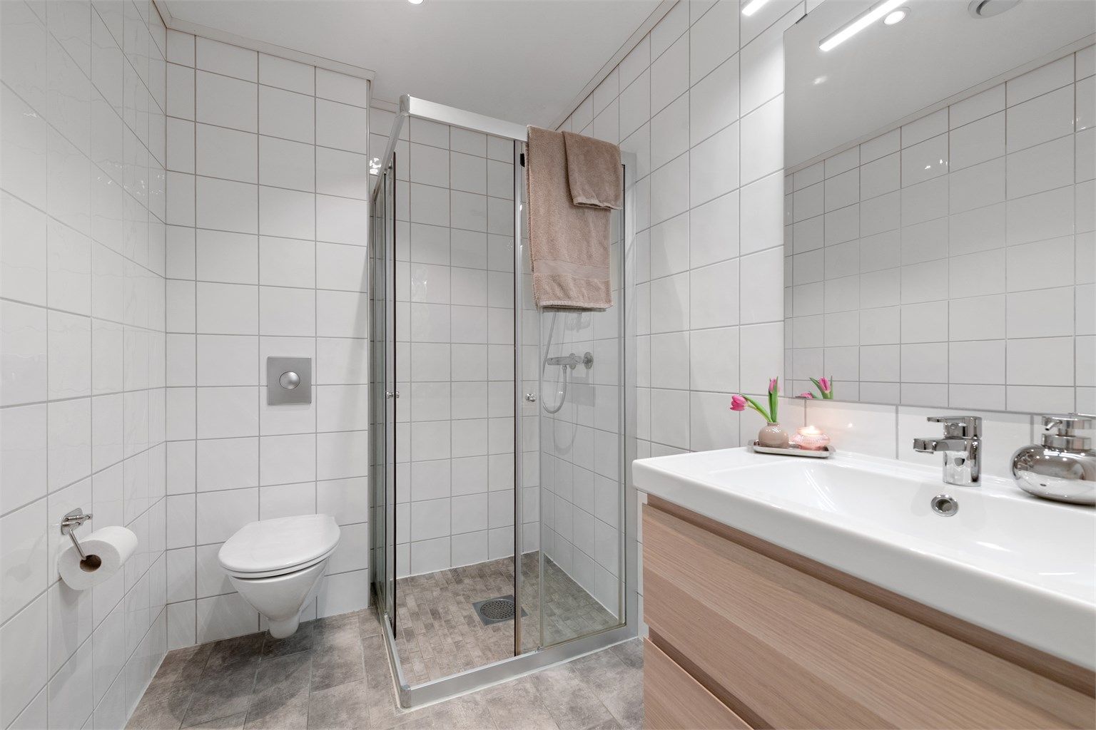 Badet i første etasje har flislagt gulv med gulvvarme, dusjhjørne og vegghengt toalett.