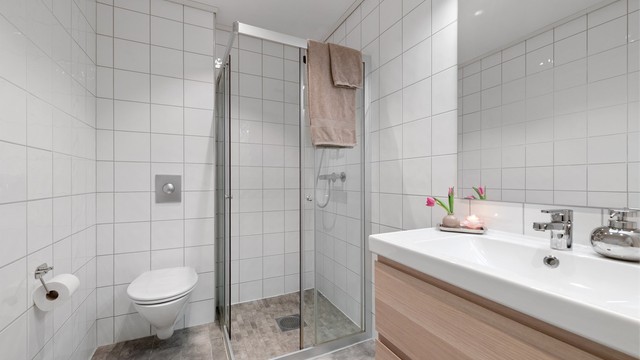 Badet i første etasje har flislagt gulv med gulvvarme, dusjhjørne og vegghengt toalett.