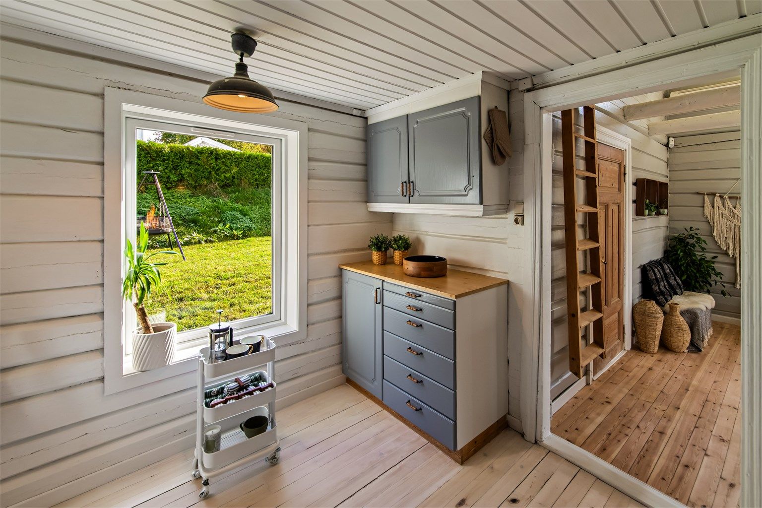Lyst kjøkken med malte overflater og klassisk tregulv. Her er det også plass til et lite spisebord.