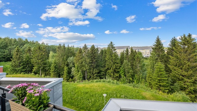 Fra takterrassen nytes et luftig utsyn mot grønne omgivelser og skogkledde områder rundt boligen.