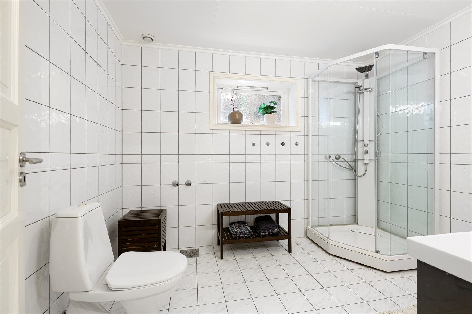 Badet i underetasjen har flislagt gulv, dusjkabinett og toalett.