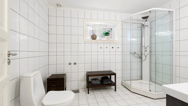 Badet i underetasjen har flislagt gulv, dusjkabinett og toalett.