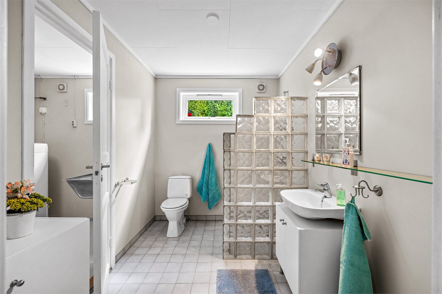 Badet har gulvvarme, dusj med vegg av glassbyggerstein og avtrekksvifte.