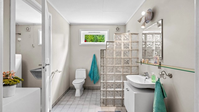 Badet har gulvvarme, dusj med vegg av glassbyggerstein og avtrekksvifte.