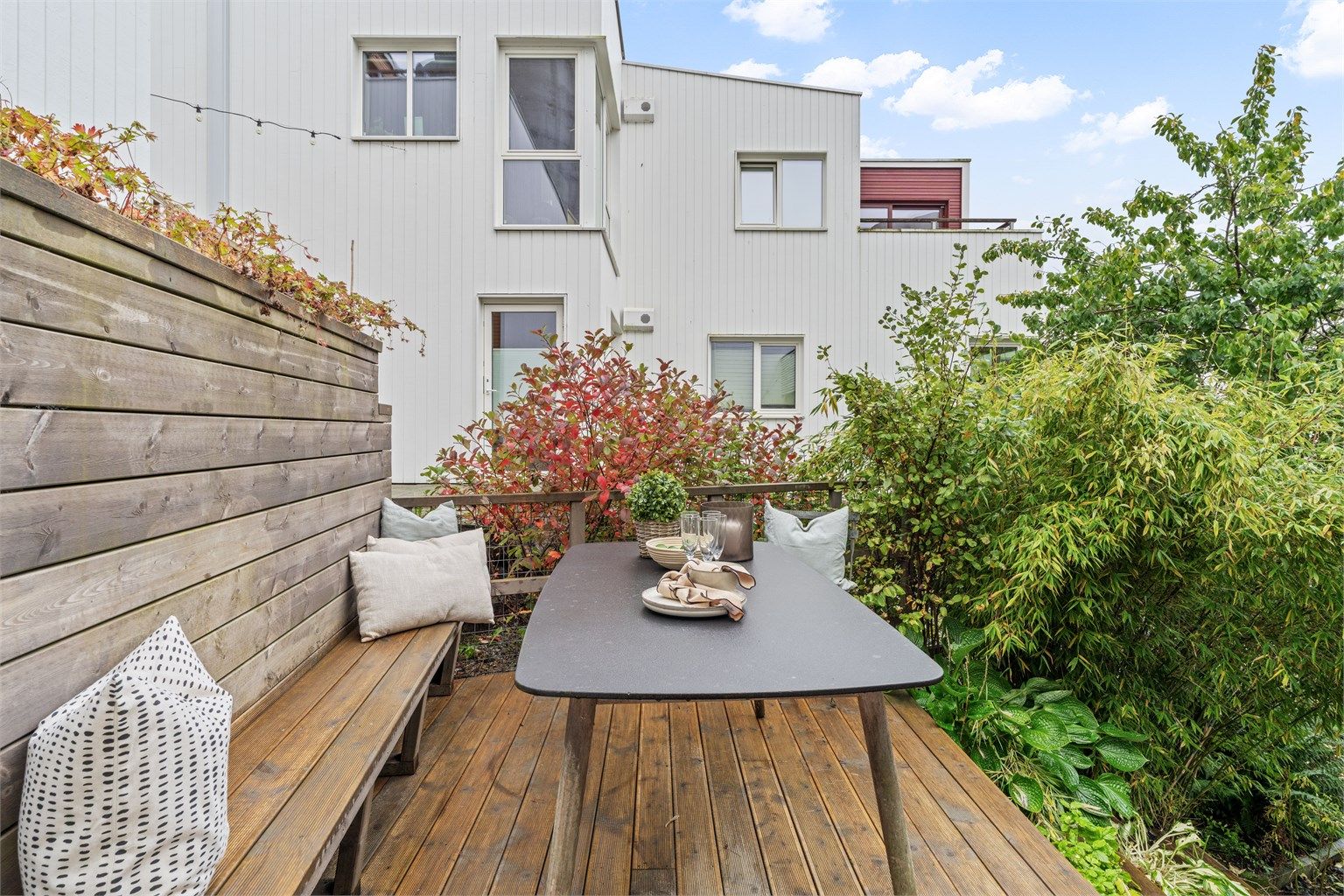 Platting i tre på baksiden av boligen med plassbygd sittebenk og spisebord.