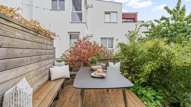 Platting i tre på baksiden av boligen med plassbygd sittebenk og spisebord.