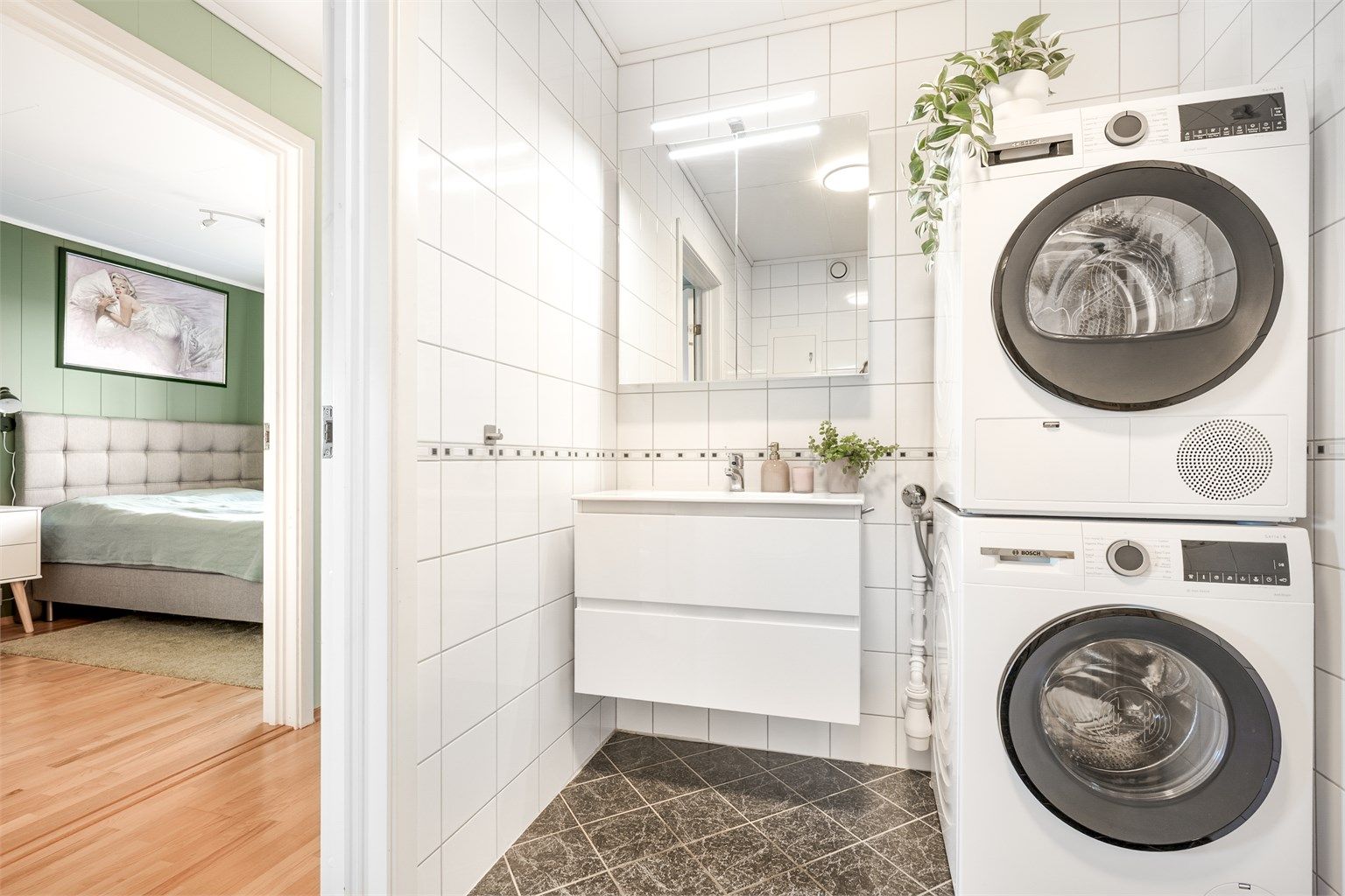 Badet har flislagt gulv med varmekabler og opplegg for vaskemaskin.