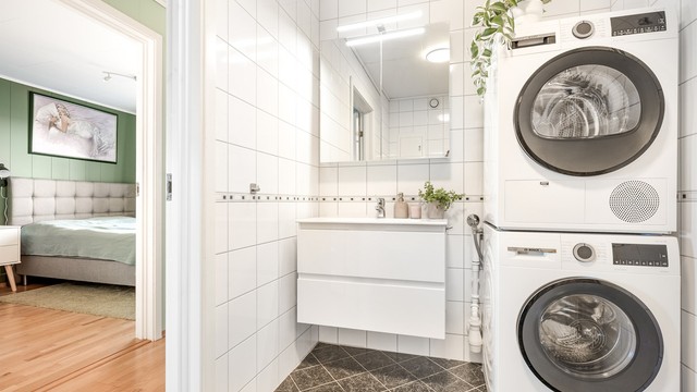 Badet har flislagt gulv med varmekabler og opplegg for vaskemaskin.