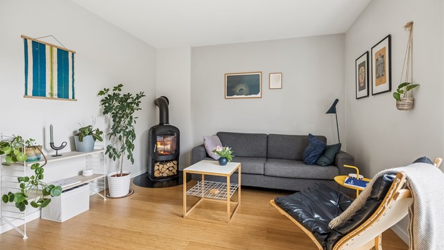 Stuen ligger lunt til i hjørnet av rommet, med god plass til sofakrok og TV. Peisen i hjørnet tilfører både varme og atmosfære.