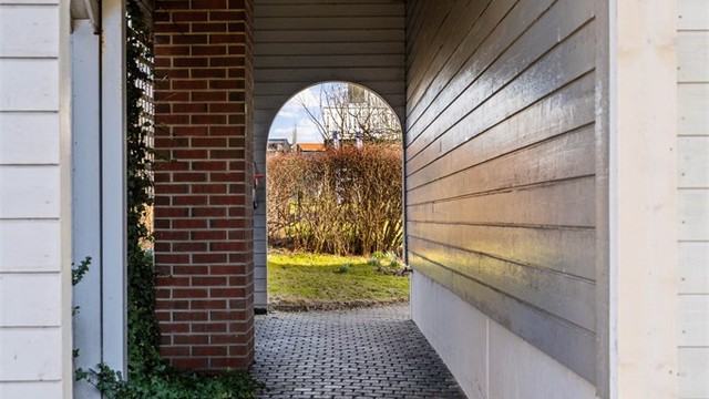 Overbygget passasje som leder fra forsiden til hagen.