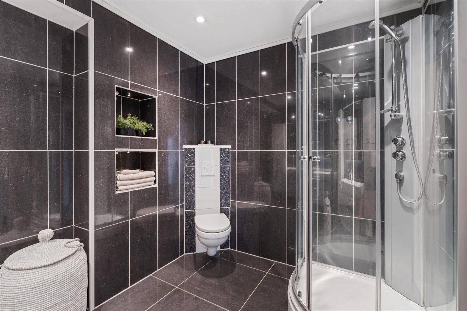 Badet er utstyrt med dusjkabinett og vegghengt toalett.