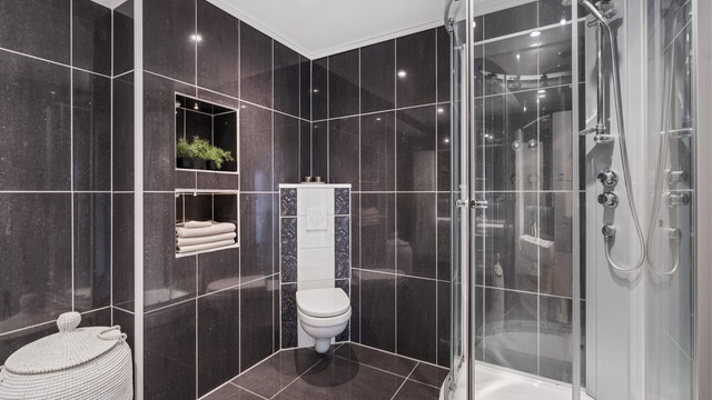 Badet er utstyrt med dusjkabinett og vegghengt toalett.