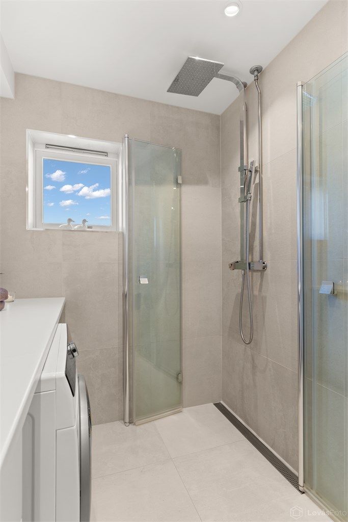 Dusjhjørne med regnfallsdusj og innfellbare glassdører for optimal plassutnyttelse.