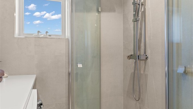 Dusjhjørne med regnfallsdusj og innfellbare glassdører for optimal plassutnyttelse.