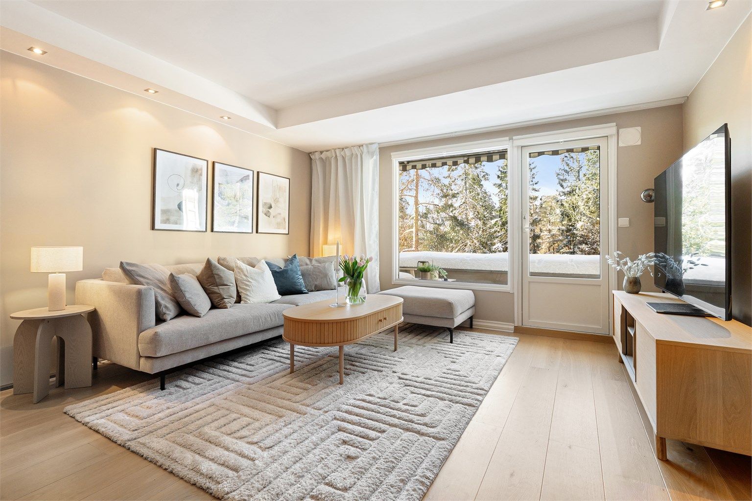 Stuen har glatte, malte flater, gjennomgående parkettgulv og store vinduer som gir en usjenert atmosfære uten innsyn.