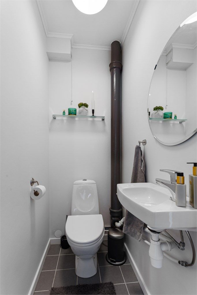 Tilliggende separat toalettrom med vegghengt servant og gulvstående toalett
