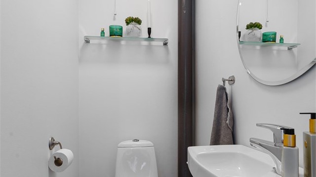 Tilliggende separat toalettrom med vegghengt servant og gulvstående toalett