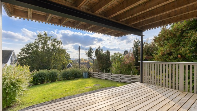 Sørvendt terrasse i 1. etasje med tredekke og trappeadkomst videre ned til hagen.
