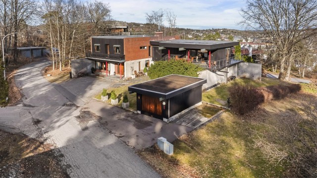 Flyfoto som viser eiendommen med garasje og gårdsplass.