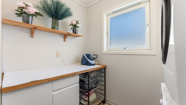 Vaskerom med fliser på gulv med gulvvarme, malte vegger, takplater i himling, baderomsmøbel, vegghengt høyskap og opplegg for vaskemaskin