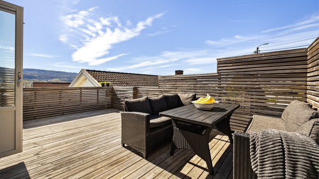 Verandaen er bygget i tre og har et rekkverk som skjermer for innsyn. Ikke byggemeldt veranda.
