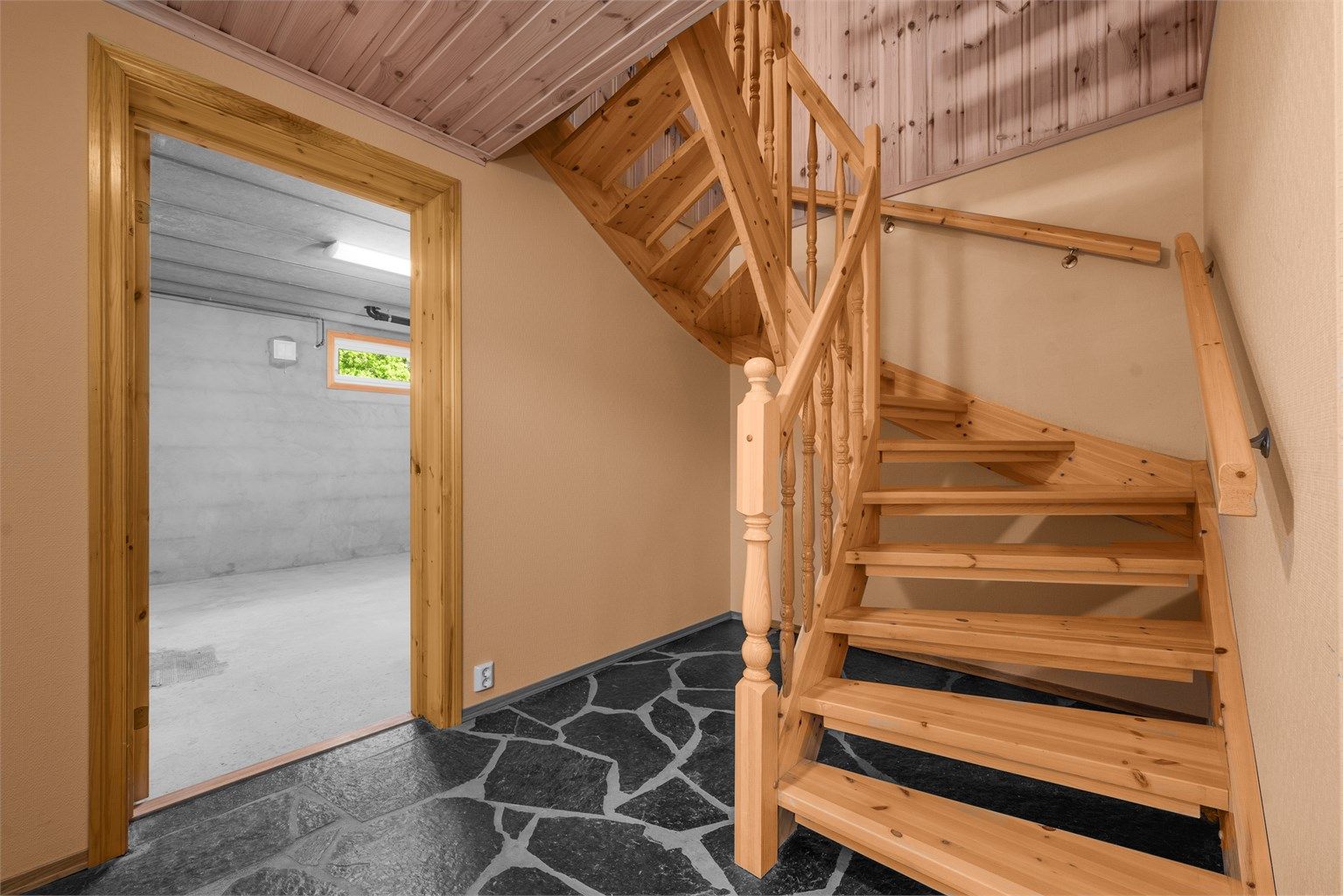 Trapperommet i kjelleren har skifergulv og leder inn til de øvrige rommene.