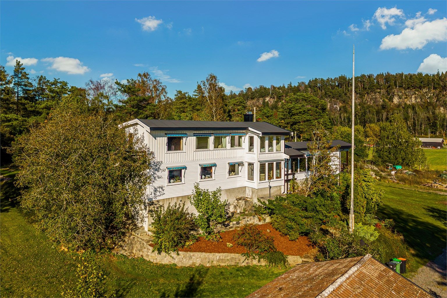 Det hvitmalte trehuset ligger på en liten kolle helt for seg selv på Rogn. 