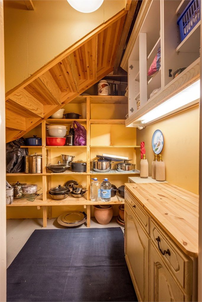 Praktisk innredet bod under trappen med fastmonterte hyller.