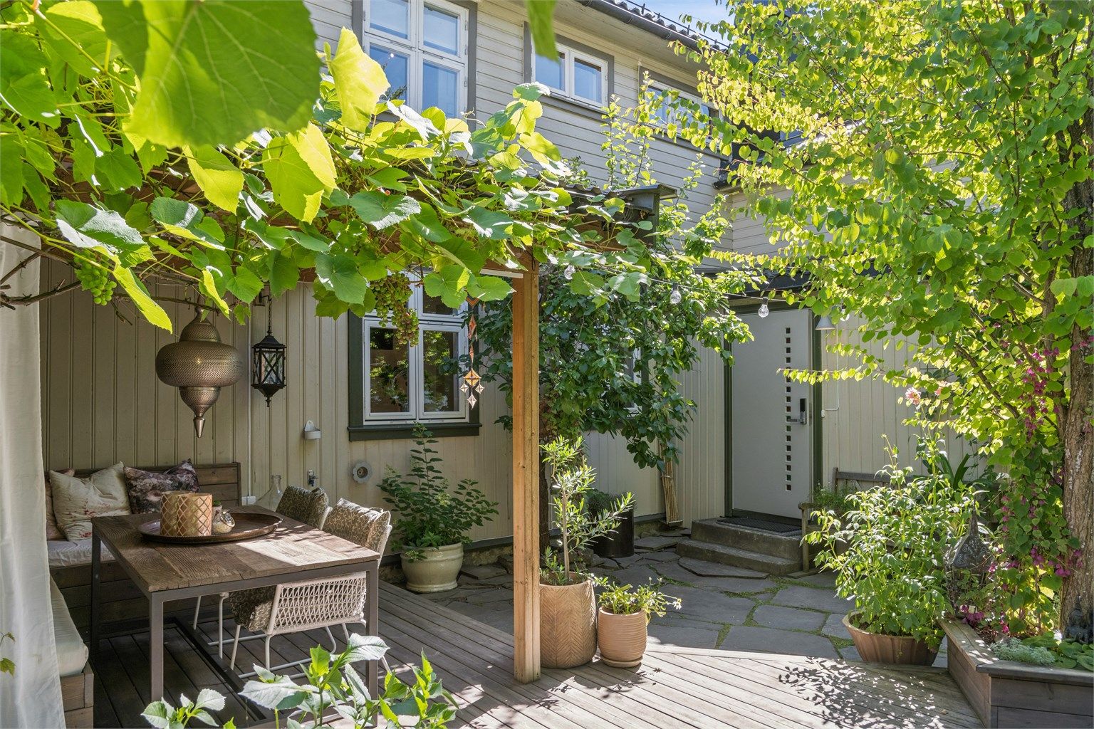 Skjermet og privat uteplass som er pent opparbeidet med platting og diverse beplantninger som plomme- og kirsebærtrær samt vindruer. 