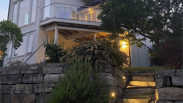 Tomten er opparbeidet med natursteinmurer og en steintrapp med belysning. Bilde tatt av selger
