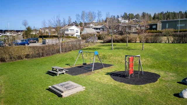 Tomten utgjør grøntarealer, adkomstveier, parkeringsområder, carportanlegg, lekeplass m.m.