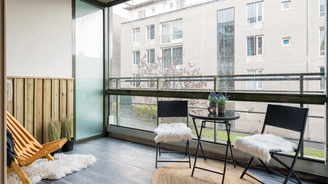 Romslig innglasset balkong med flisbelagt gulv og nye panelbord på vegg