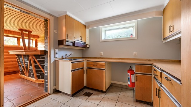 Innredet rom i kjelleren med kjøkkeninnredning. Boligens nye varmtvannstank fra 2024 er plassert her. (Ikke godkjent til varig opphold)