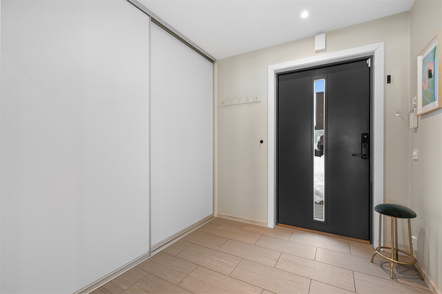 Entré med flislagte gulv med varme og god plass til å henge fra seg yttertøy i praktisk skyvedørsgarderobe