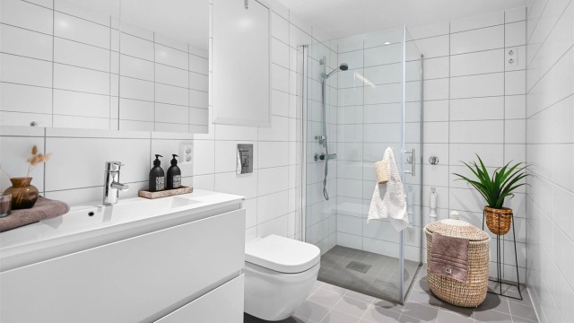 Moderne og romslig helfliset bad med opplegg for vaskemaskin