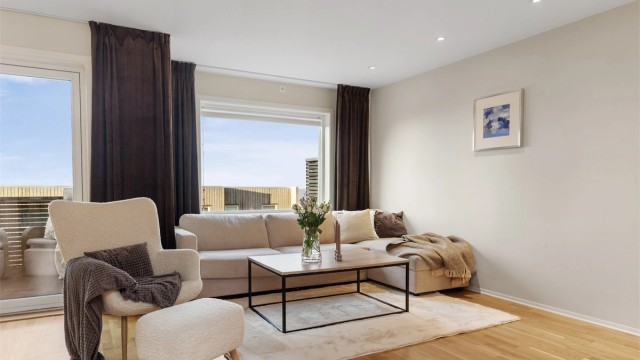 Stuen har også en romslig sofakrok og direkte utgang til solrik balkong med flott sjøutsikt.