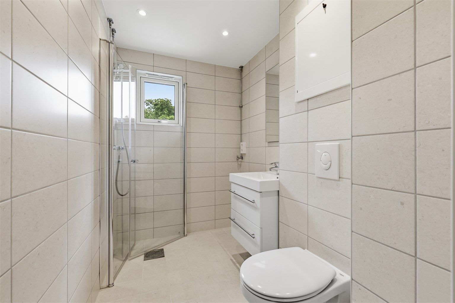 Badet er oppgradert i regi av borettslaget, med fliser på gulv og vegger og en praktisk dusjløsning.
Foto: Digit Media