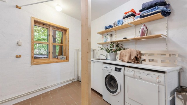 Vaskerom fra byggeår med flislagt gulv og gulvvarme. Malte veggflater og malt himlingsflate. Vegghengt servant med armatur, dusjkabinett med dusjarmatur og gulvstående toalett. Benkeskap med laminert benkeplate, utslagsvask med armatur og opplegg for vask