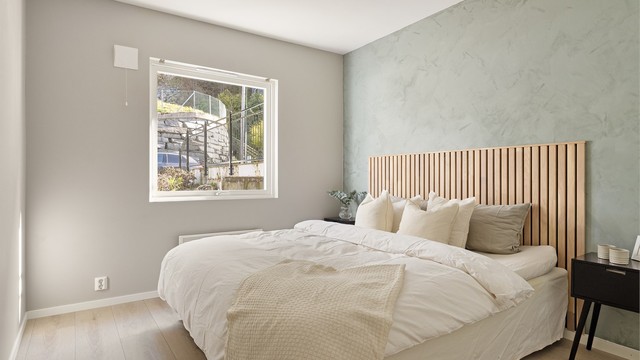 Innbydende soverom med lysmalte overflater og en superfin eikefarget sengegavl.